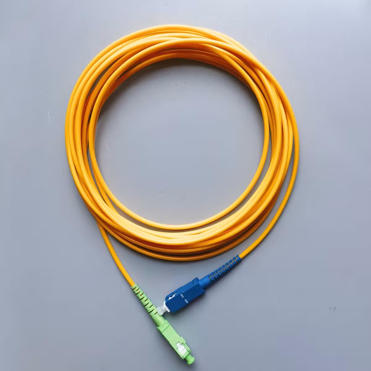 Patch cord SC/UPC към SC/APC 10 m, OS2 9/125 μm, LSZH, simplex Оптичен patch cord SC/UPC към SC/APC 10 m, едномодов OS2 9/125 μm, жълт кабел със син и зелен конектор за свързване между отдалечен ODF и устройство